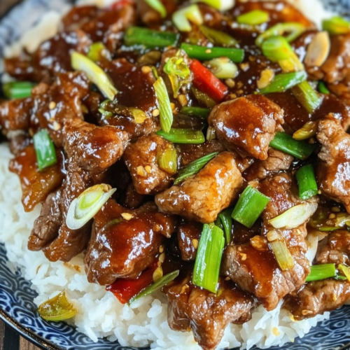 Spicy scallion beef stir-fry served over fluffy white rice in a patterned blue bowl.
