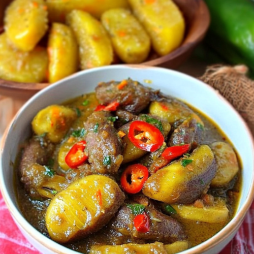 Authentic Filipino Saging at Ginamos served in a white bowl with sliced red chilies, herbs, and a savory sauce, alongside a wooden plate of whole cooking bananas