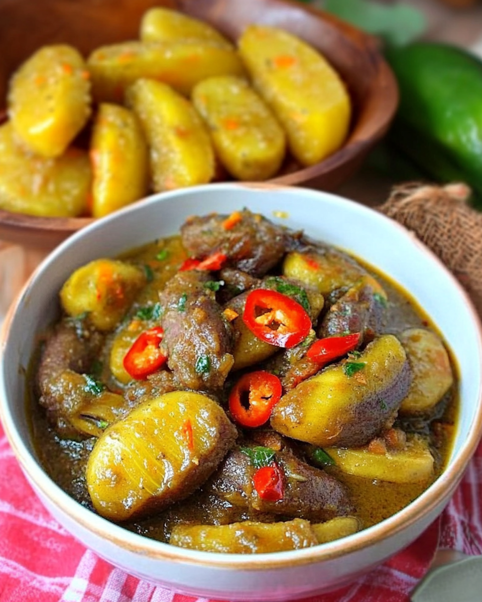 Authentic Filipino Saging at Ginamos served in a white bowl with sliced red chilies, herbs, and a savory sauce, alongside a wooden plate of whole cooking bananas