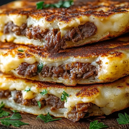 Close-up of crispy golden potato pancakes stuffed with seasoned beef and melted cheese, garnished with fresh parsley.